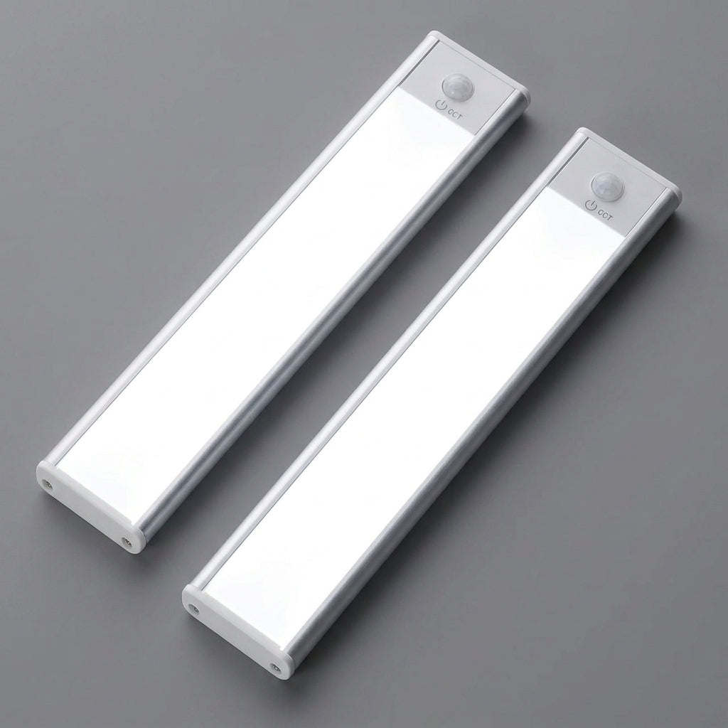 AMBIENTIFY Sora slim rechargeable LED light bar mounted beneath a wooden shelf above a home desk, casting warm even light across the workspace — motion sensor under-cabinet lighting in brushed aluminium.