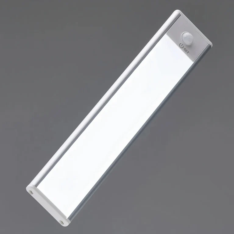 AMBIENTIFY Sora slim rechargeable LED light bar mounted beneath a wooden shelf above a home desk, casting warm even light across the workspace — motion sensor under-cabinet lighting in brushed aluminium.