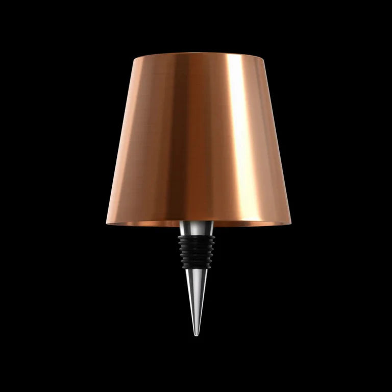 AMBIENTIFY Bottle wireless LED lamp fitted onto a wine bottle, placed on an outdoor garden table surrounded by natural greenery. Soft warm ambient glow, touch-dimmable in 3 levels, USB-C rechargeable table lamp for home décor.