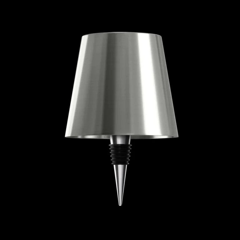 AMBIENTIFY Bottle wireless LED lamp fitted onto a wine bottle, placed on an outdoor garden table surrounded by natural greenery. Soft warm ambient glow, touch-dimmable in 3 levels, USB-C rechargeable table lamp for home décor.