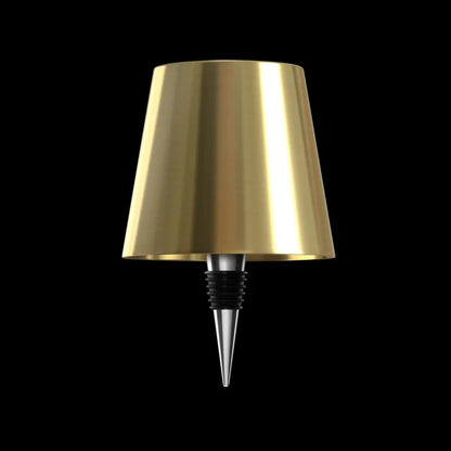 AMBIENTIFY Bottle wireless LED lamp fitted onto a wine bottle, placed on an outdoor garden table surrounded by natural greenery. Soft warm ambient glow, touch-dimmable in 3 levels, USB-C rechargeable table lamp for home décor.