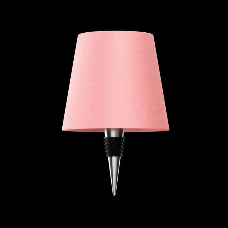 AMBIENTIFY Bottle wireless LED lamp fitted onto a wine bottle, placed on an outdoor garden table surrounded by natural greenery. Soft warm ambient glow, touch-dimmable in 3 levels, USB-C rechargeable table lamp for home décor.