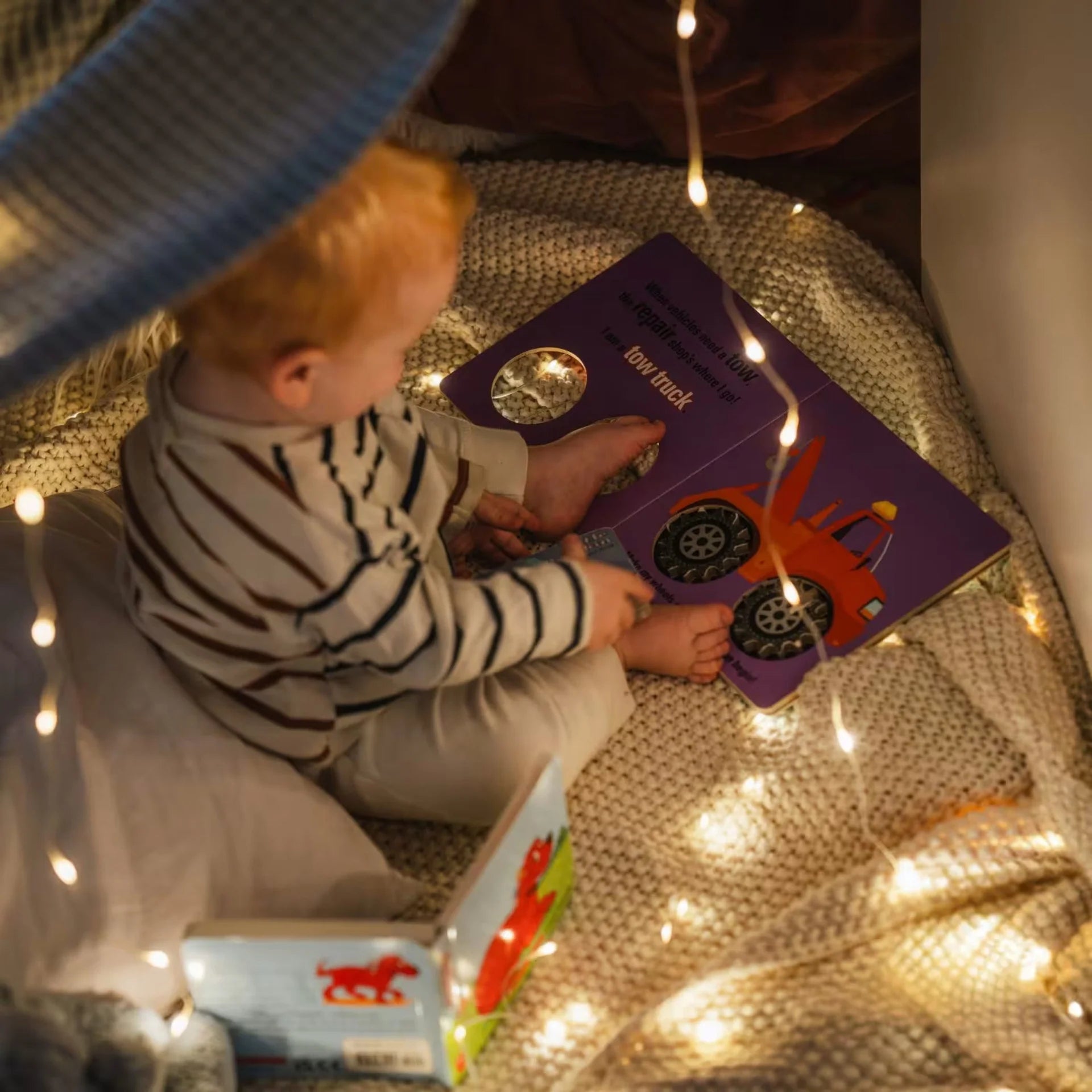 Campify String fairy light reel held in hand at night, showing warm amber LED string lights extended across dark outdoor ground, compact hub glowing with blue charge indicator, IP67 waterproof camping and home fairy lights.