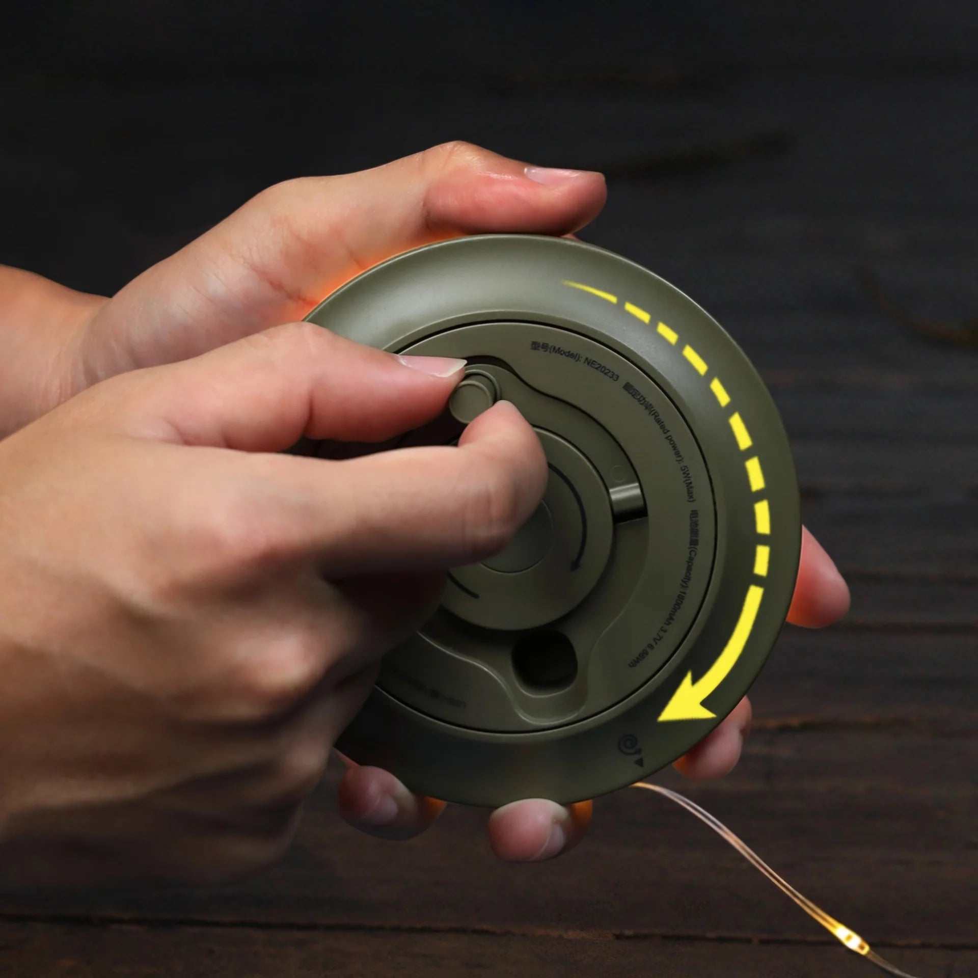 Campify String fairy light reel held in hand at night, showing warm amber LED string lights extended across dark outdoor ground, compact hub glowing with blue charge indicator, IP67 waterproof camping and home fairy lights.