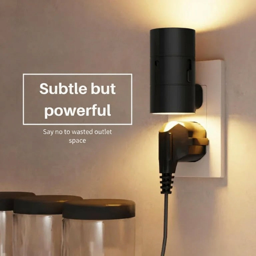 PLUGIFY One plug-in wall light in matte finish mounted in a bedroom wall socket, casting warm ambient light onto a wooden bedside table with a remote control and ceramic mug beside it.