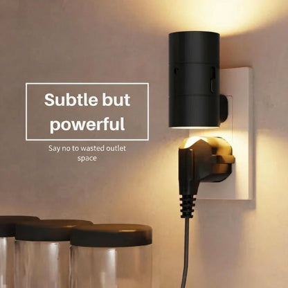 PLUGIFY One plug-in wall light in matte finish mounted in a bedroom wall socket, casting warm ambient light onto a wooden bedside table with a remote control and ceramic mug beside it.