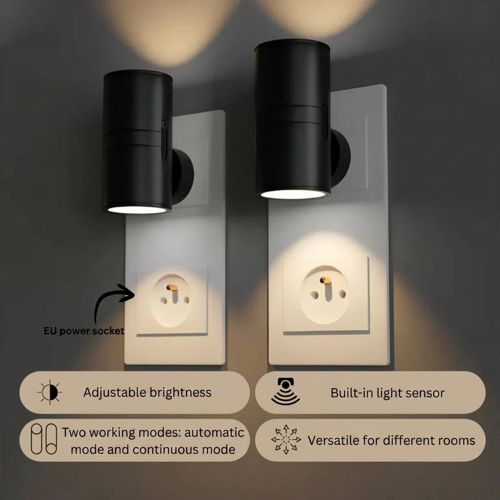 PLUGIFY One plug-in wall light in matte finish mounted in a bedroom wall socket, casting warm ambient light onto a wooden bedside table with a remote control and ceramic mug beside it.