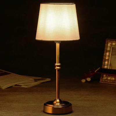 AMBIENTIFY Classic cordless table lamp with fabric shade and iron stem, casting warm ambient light on a bedside table. Three brightness settings and up to 40 hours battery life. Suitable for bedroom, living room and home office.
